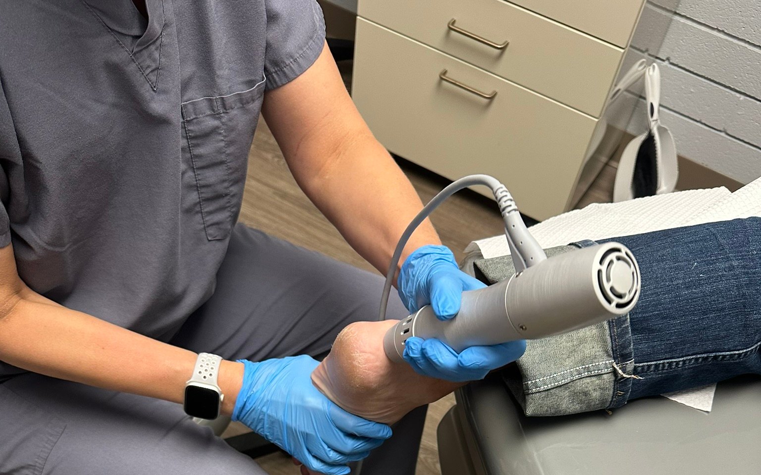 Dr. Korves applying the ESWT handpiece to an anonymous patient’s heel in the treatment room